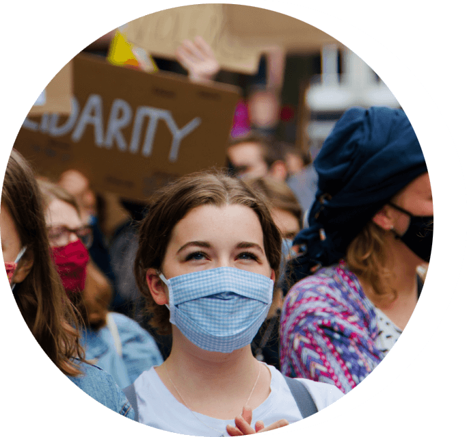 A group of people wearing masks and holding signs.